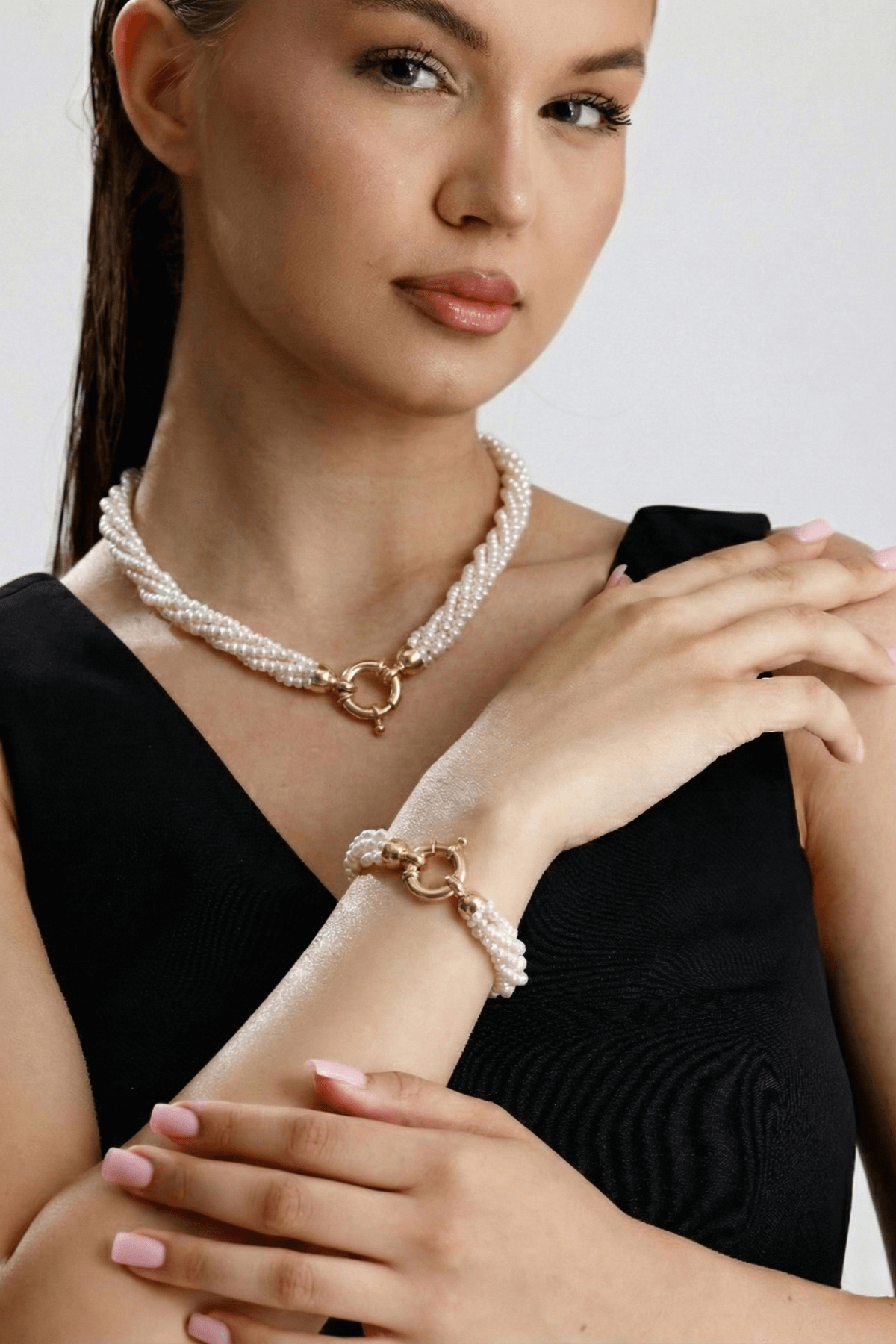 Doğal inci burgu bileklik ve inci kolye takan kadın modeli, şık görünüm.