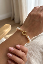 Natural pearl bracelet displayed on a woman's wrist with a gold clasp.