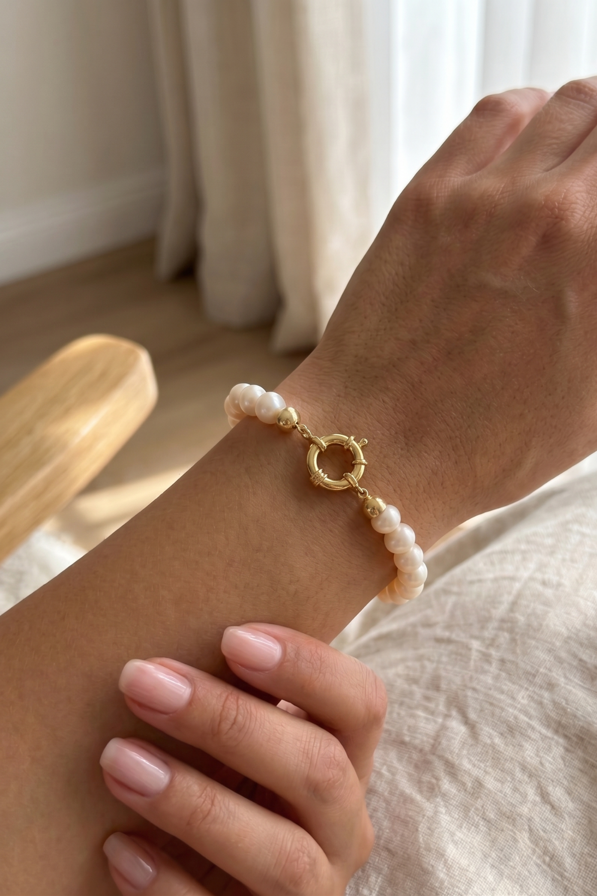 Natural pearl bracelet displayed on a woman's wrist with a gold clasp.