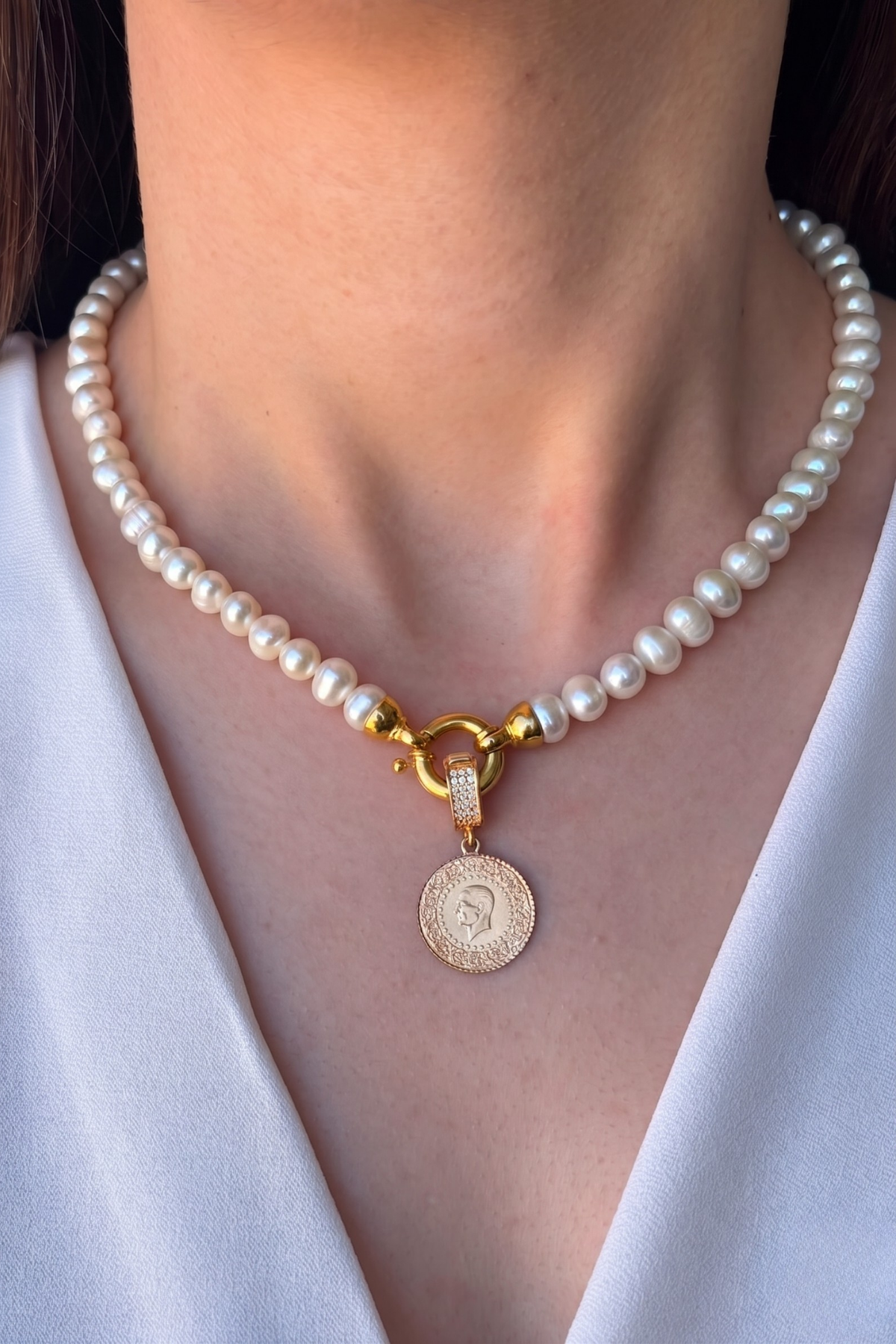 natural pearl necklace with quarter gold featuring a gold charm and clasp, worn elegantly.
