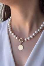 Natural pearl necklace with quarter gold featuring a charm and elegant design on a model.