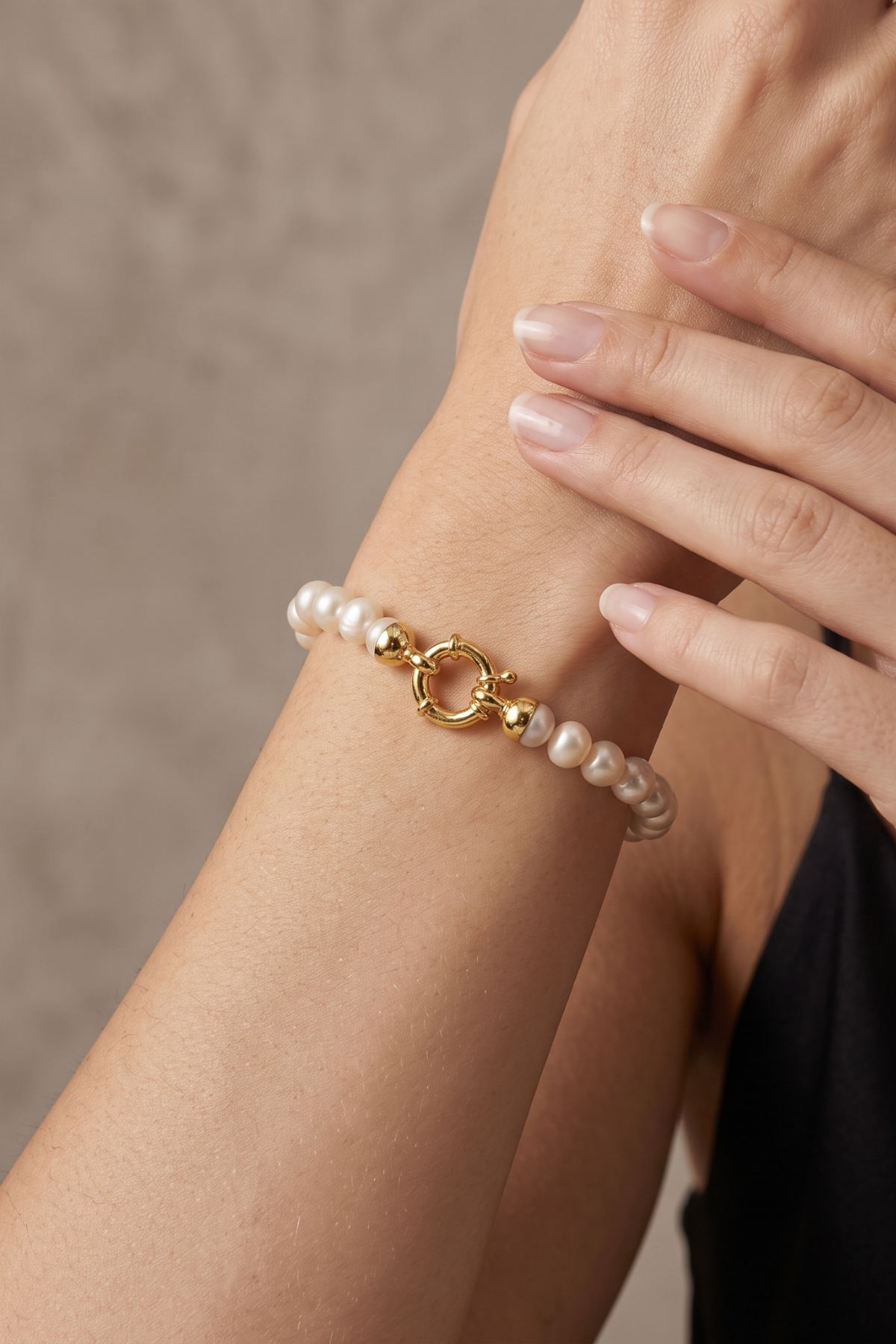 Natural pearl bracelet displayed on a woman's wrist with a gold clasp against a neutral background.