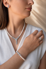 Natural pearl jewelry set worn by a model, featuring a necklace, bracelet, and earrings on a light background.