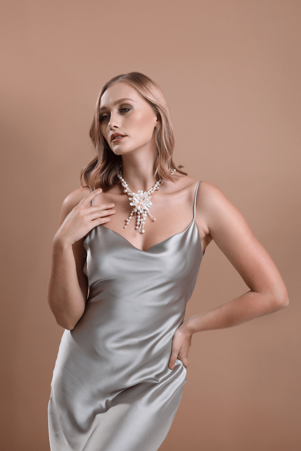Barok Buketi Doğal İnci Kolye takmış bir kadın, şık gümüş elbise ile poz veriyor.