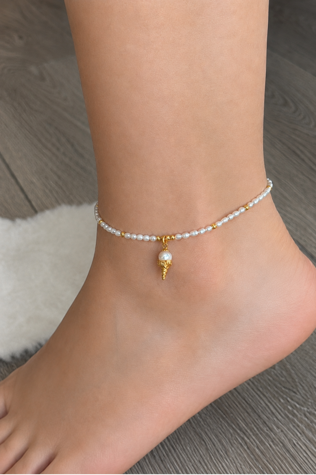 Creamy doğal inci halhal with golden charm worn on an ankle, showcasing elegant design and natural pearls.