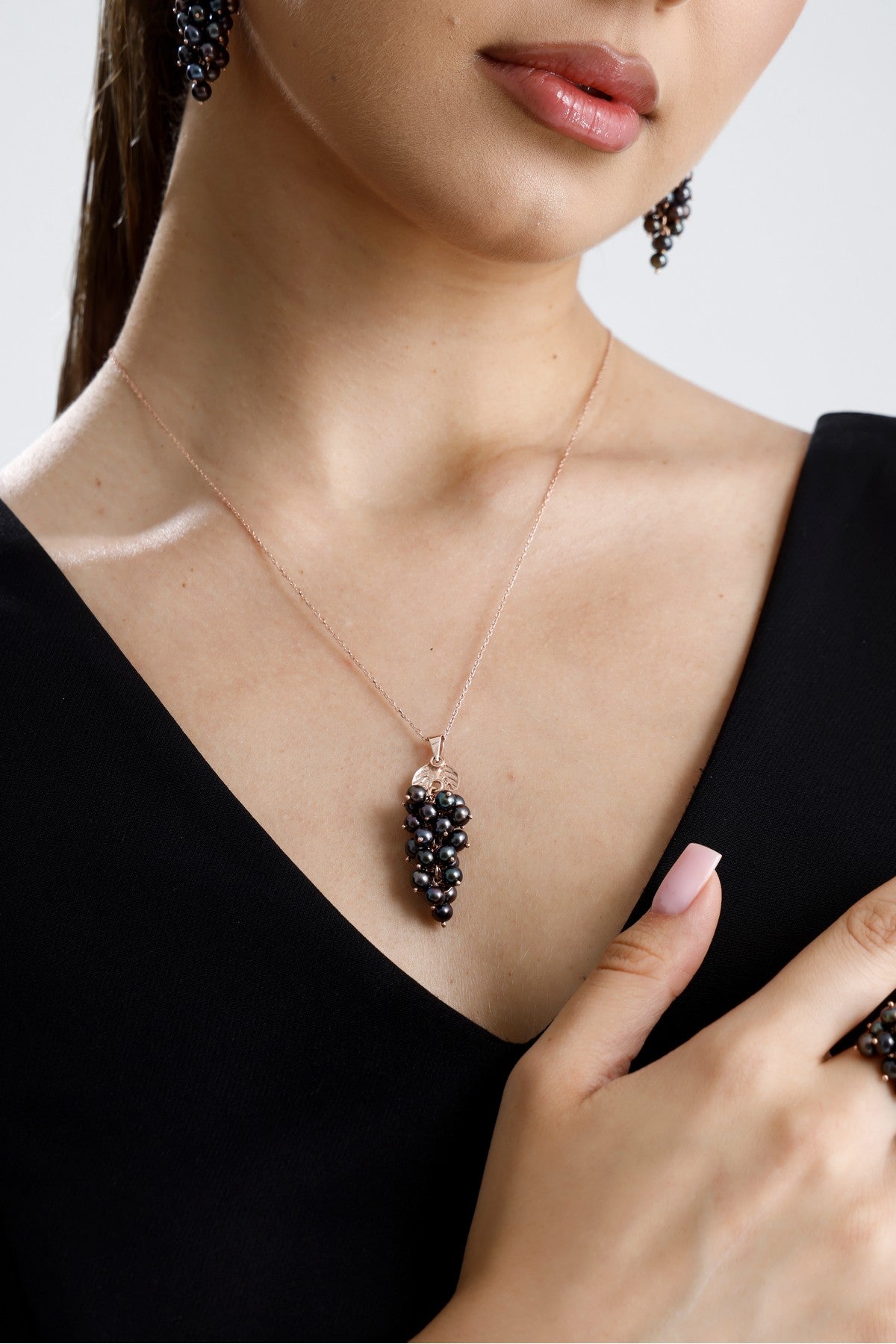 Model wearing a natural pearl grape cluster necklace with a stylish design on a black outfit.